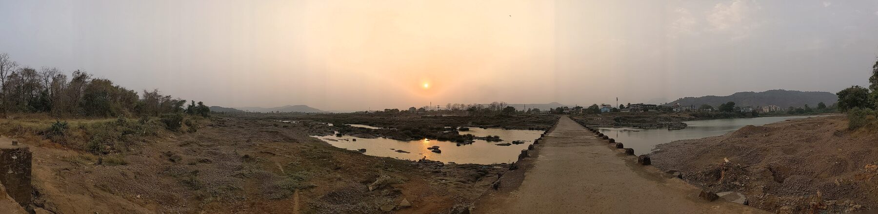 A causeway crossing water near Birwadi at sunset